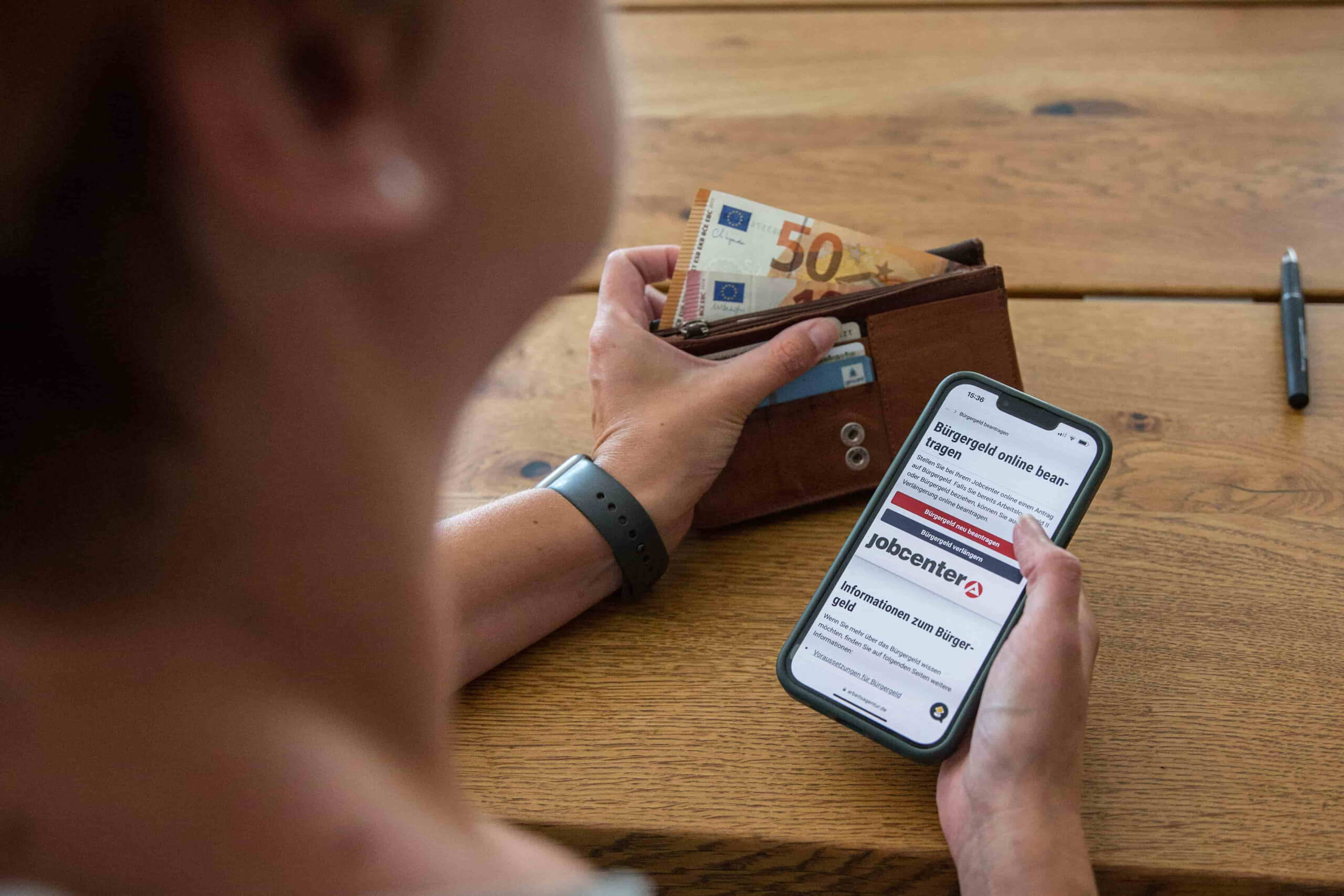 Person hält ein Smartphone, das ein Webseite der Bundesagentur für Arbeit zeigt.