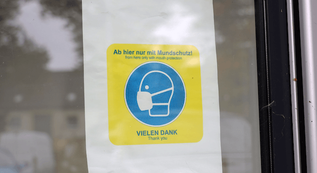 Auf einem Schild steht: "Ab hier nur mit Mundschutz"